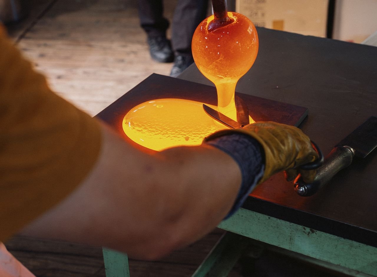 Close-up of glassmaking in Nagano, Japan. Artisan shaping molten glass with precision tools.